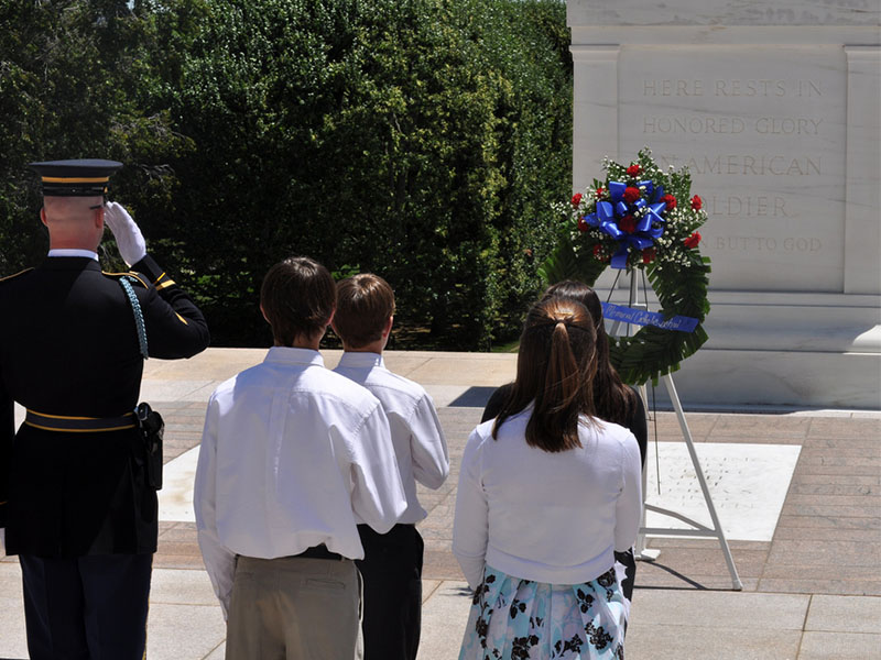 Four middle school students place a wreath with an honor guard in salute at the Tomb of the Unknown Soldier at Arlington National Cemetery