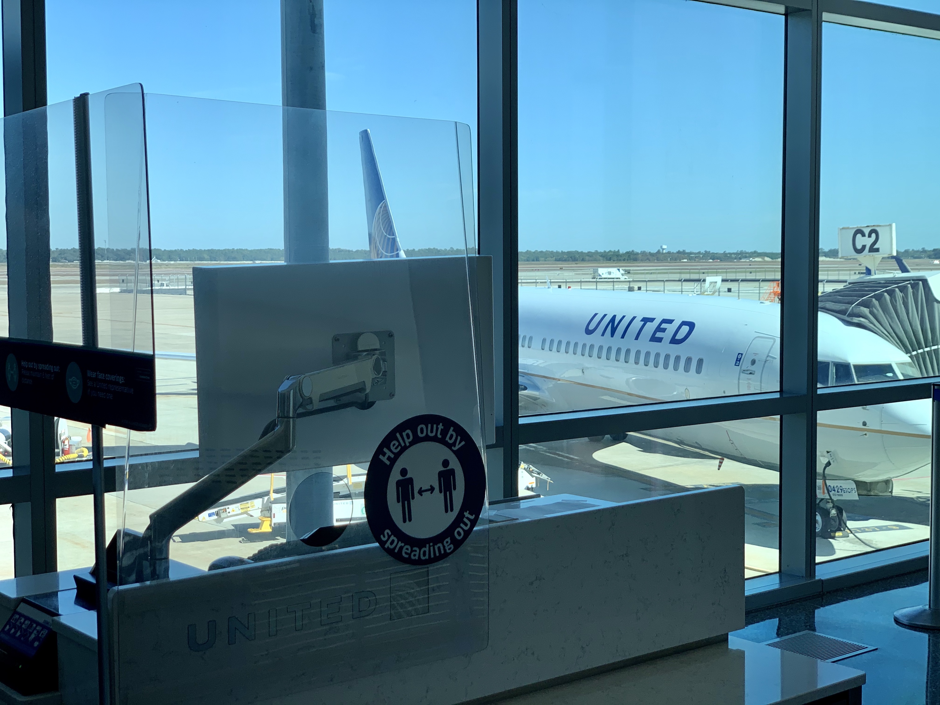 Plexiglass surrounds the boarding staging area to limit contact between passengers and airlines staff.