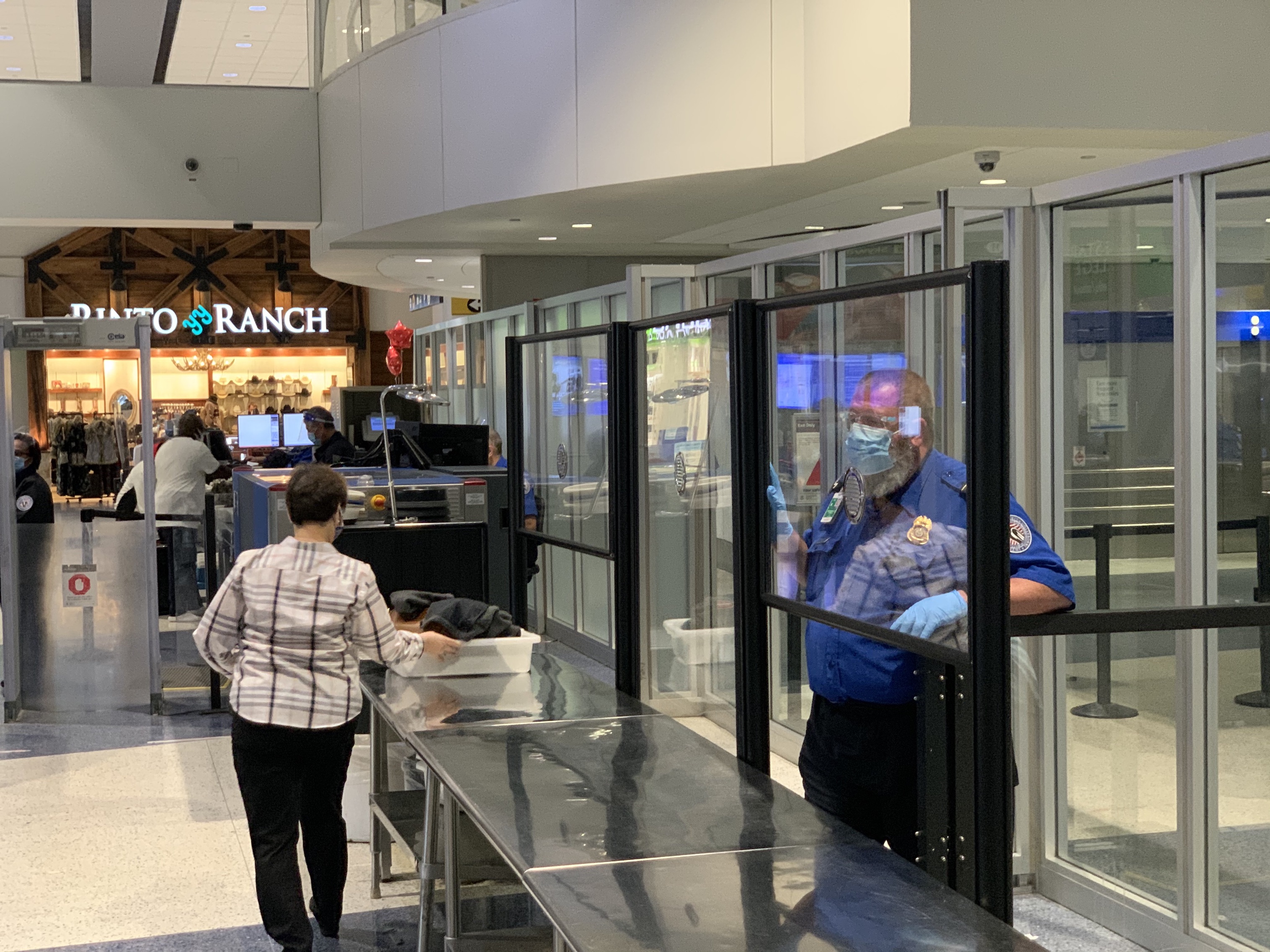 A passenger walks through the TSA security check point with plexiglass barriers in place to keep everyone safe.